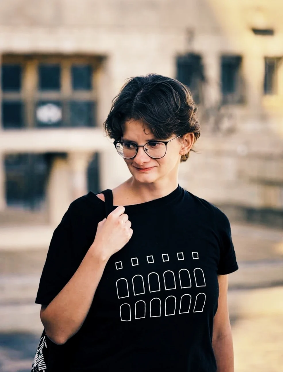 Kate exploring a city, wearing glasses and a black T-shirt